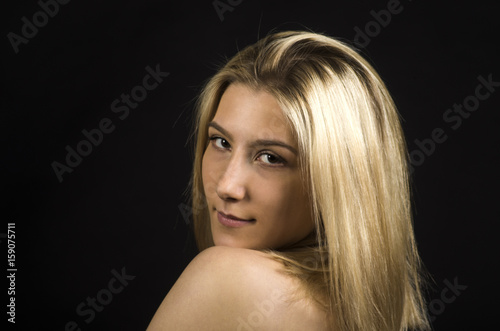 Portrait of a smiling girl on a dark background.