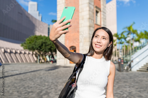Woman taking selfie in Hong Kong with clock tower