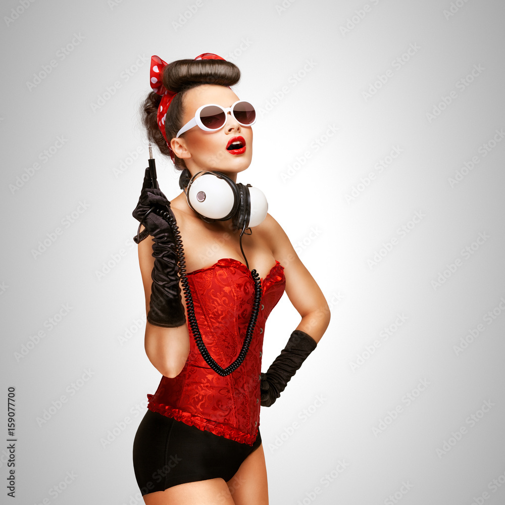 Pin-up party / Retro photo of a pin-up girl with big vintage music headphones on grey background.