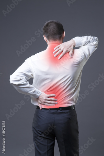Back pain, man with backache on gray background