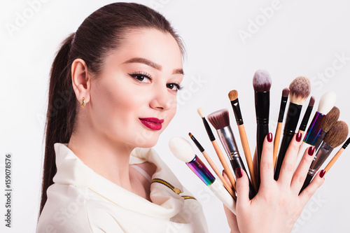 Makeup artist with brushes in hand on a white background