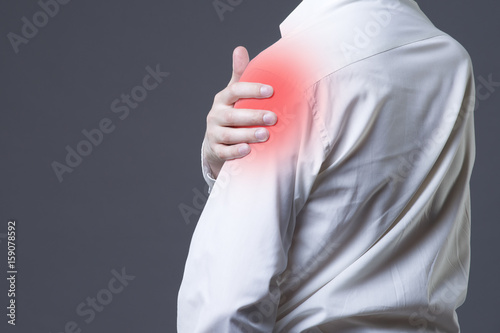 Man with pain in shoulder on gray background