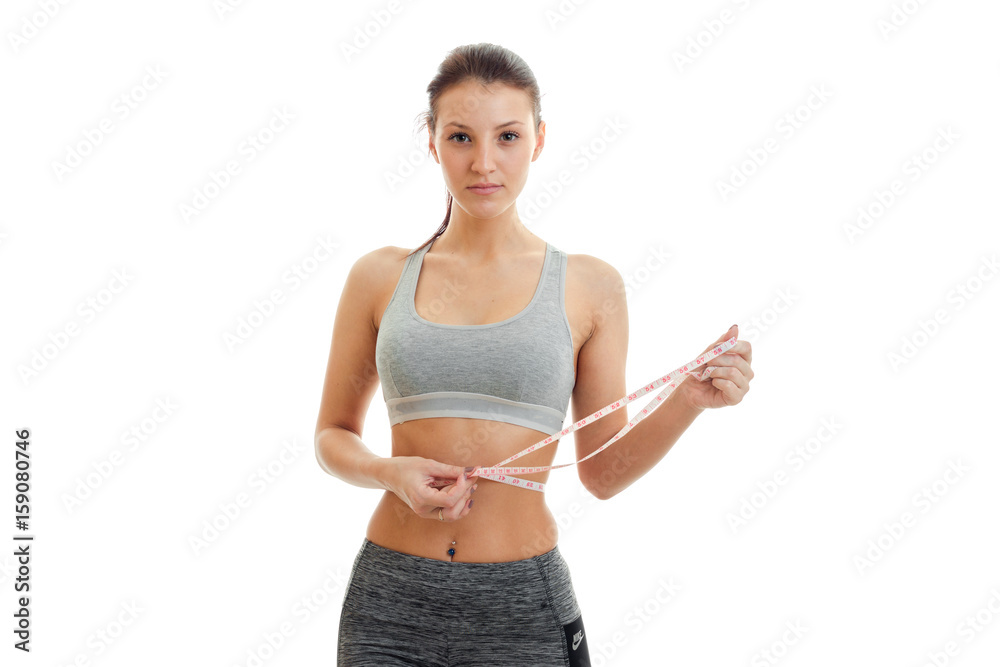 beautiful young girl holding a measuring tape and stares into the camera close-up beautiful young girl holding a measuring tape and stares into the camera close-up