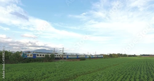 Passenger train is passing over the green meadow in the countryside. photo