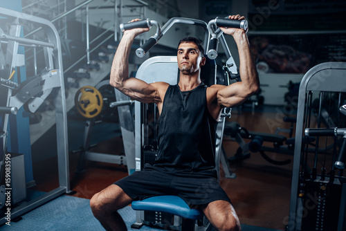 Tanned man training on exercise machine