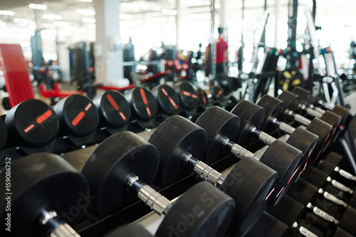 Background image: row of dumbbells on rack in empty modern gym