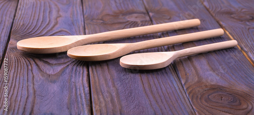 Three wooden spoons on a wooden table.