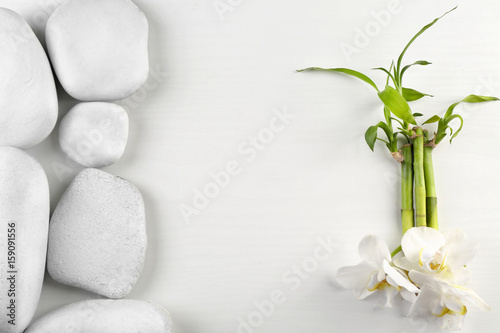Spa stones with orchid flowers and bamboo stem on white background