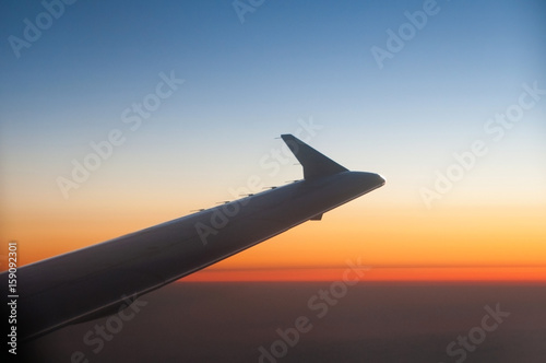 Wing of a Airplane at sunset with clouds