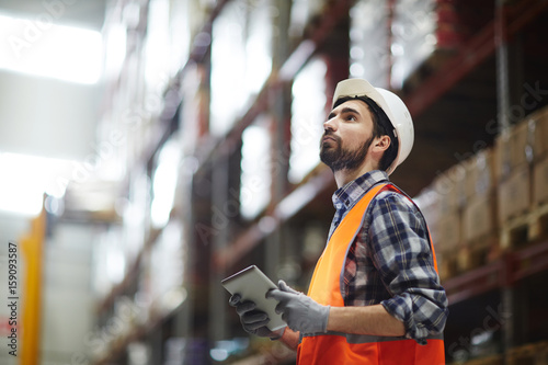 Konstfotografi Worker with touchpad revising goods in storehouse