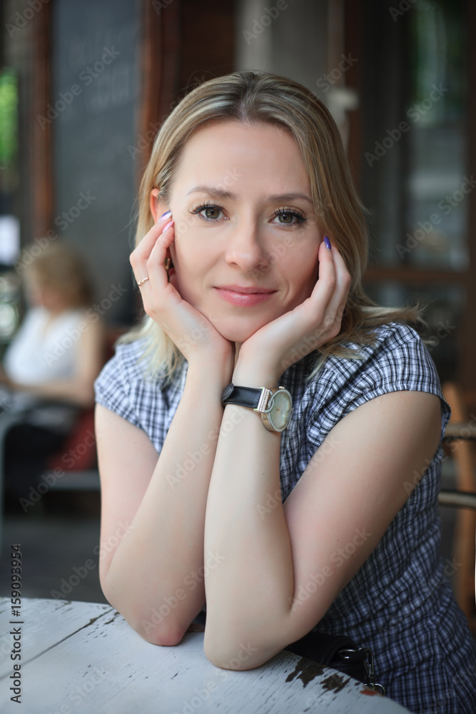Fashion portrait of young woman sitting in a street cafe.