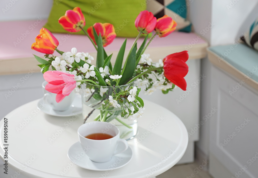 Vase with beautiful flowers and tea set on table in modern veranda interior