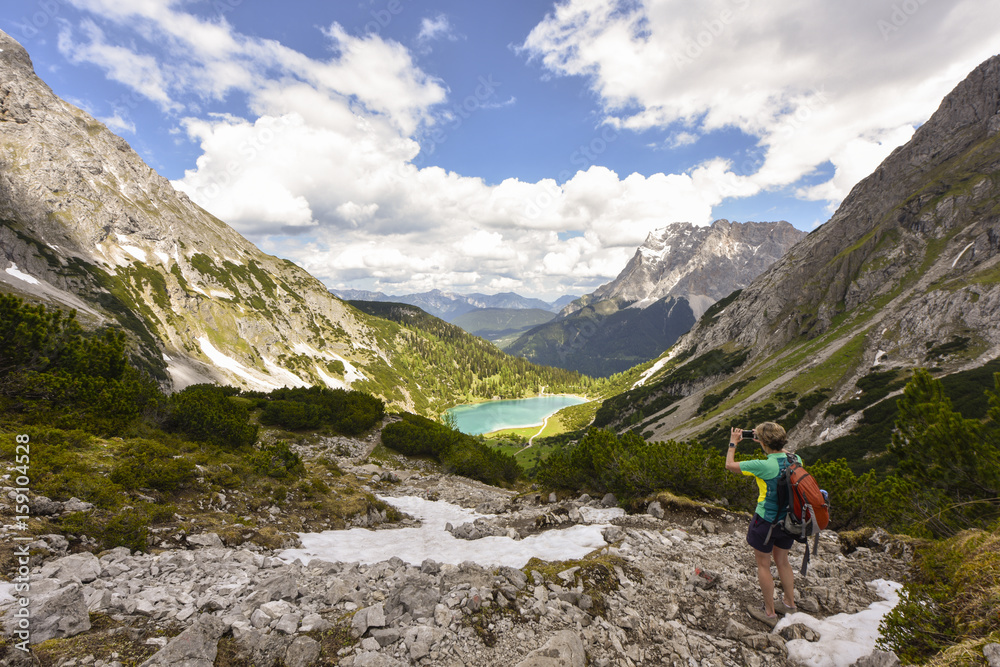 Woman taking picture of Zugspitze mountain range and lake Seebensee, Ehrwald inTyrol, Austria