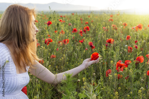 Woman in poppy field holding one poppy © Sebastian Studio