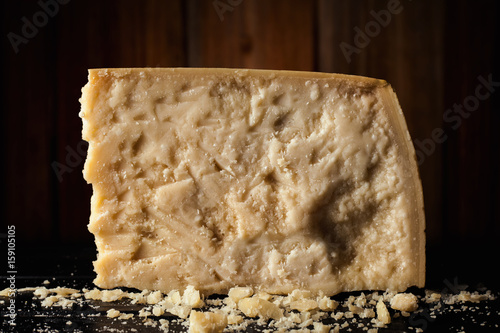 Slice of parmesan cheese with wooden background