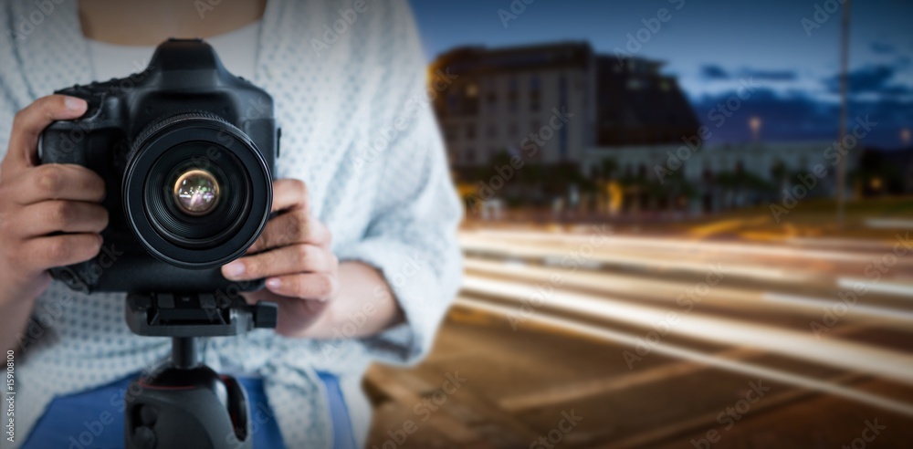 Composite image of mid section of woman holding digital camera 