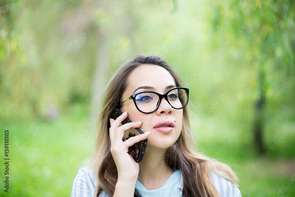 outside portrait of beautiful young curly woman talking over mobile phone in park outside portrait of beautiful young curly woman talking over mobile phone in park