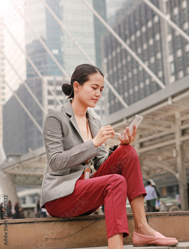 Beautiful business woman sitting and working on a smartphone in her hands outdoors.