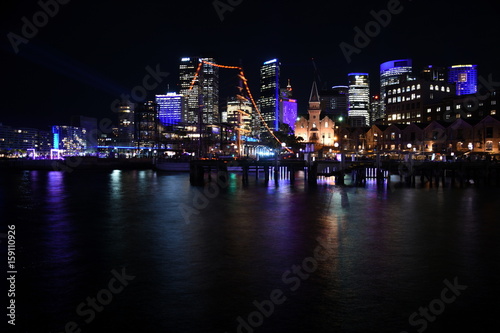 Beautiful scene of colorful Sydney city skyline by night at Campbell s Cove during Vivid Sydney Lights Festival. Free annual outdoor event of light music and ideas.