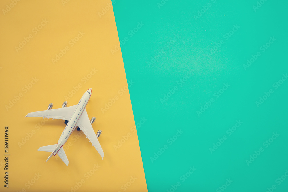 Flat lay design of travel concept with plane on green and yellow background with copy space.
