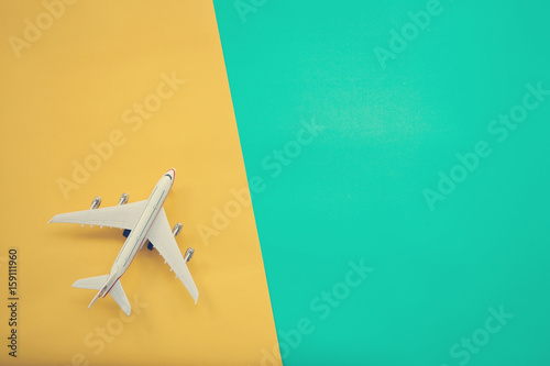 Flat lay design of travel concept with plane on green and yellow background with copy space.