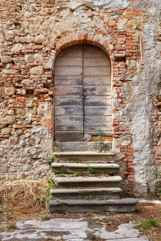 Old wooden door of a run down house in Tuscany, Italy.
