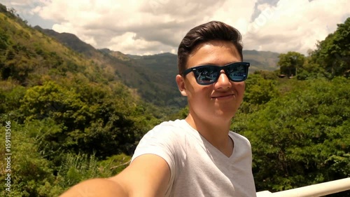 Teenage boy taking selfie, recording video with valley view, super slow motion 240fps 
