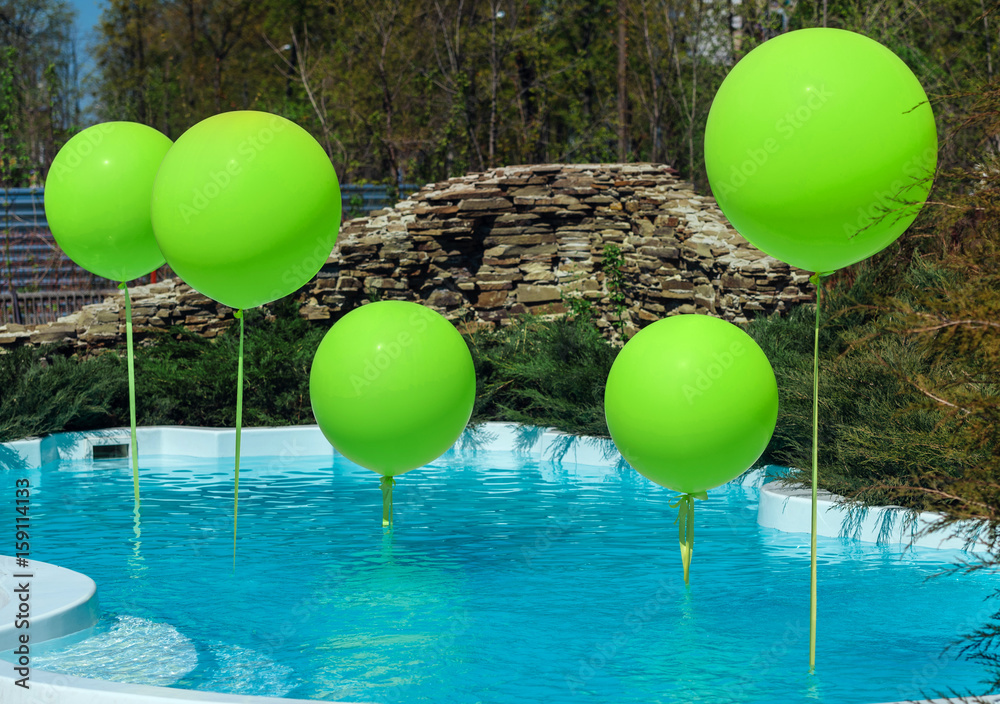 Pool with big green balloons outdoor. Poolside party. The balloons on