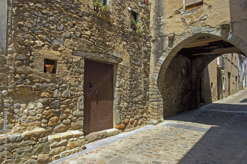 Angles pueblo de Girona calle principal con arcada de piedra muy antigua