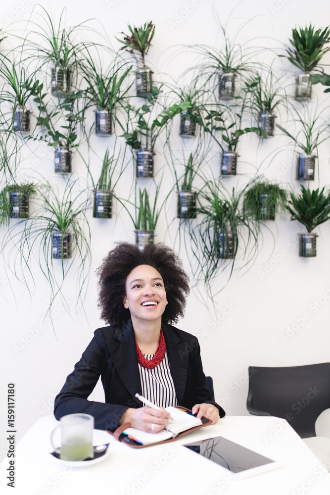 Confident and smiled cute Afro american business woman sitting in modern cafe and using her laptop or tablet. Confident and smiled cute Afro american business woman sitting in modern cafe and using her laptop or tablet.