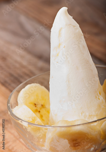 Ice cream with banana slices on an old wooden background.