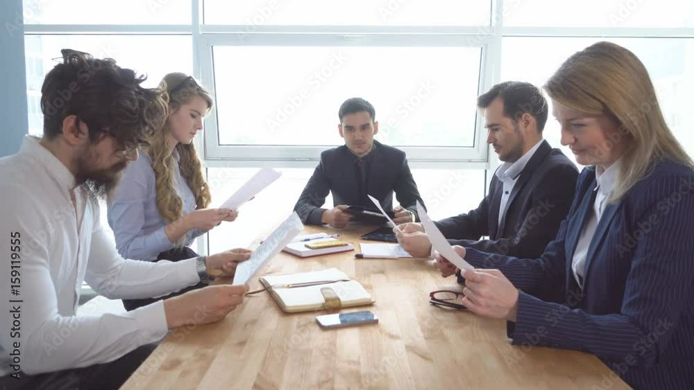 Colleagues look through documents. a business meeting. Group of young businessman at the negotiating table in the office. Colleagues look through documents. a business meeting. Group of young businessman at the negotiating table in the office.