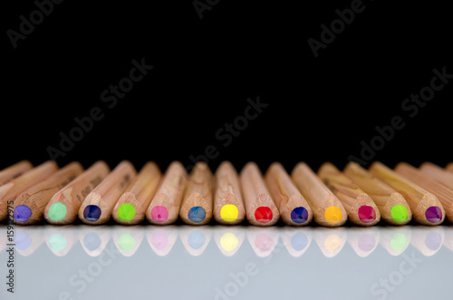 Photography Close-up view of colored pencils lying on glossy white background with reflectio