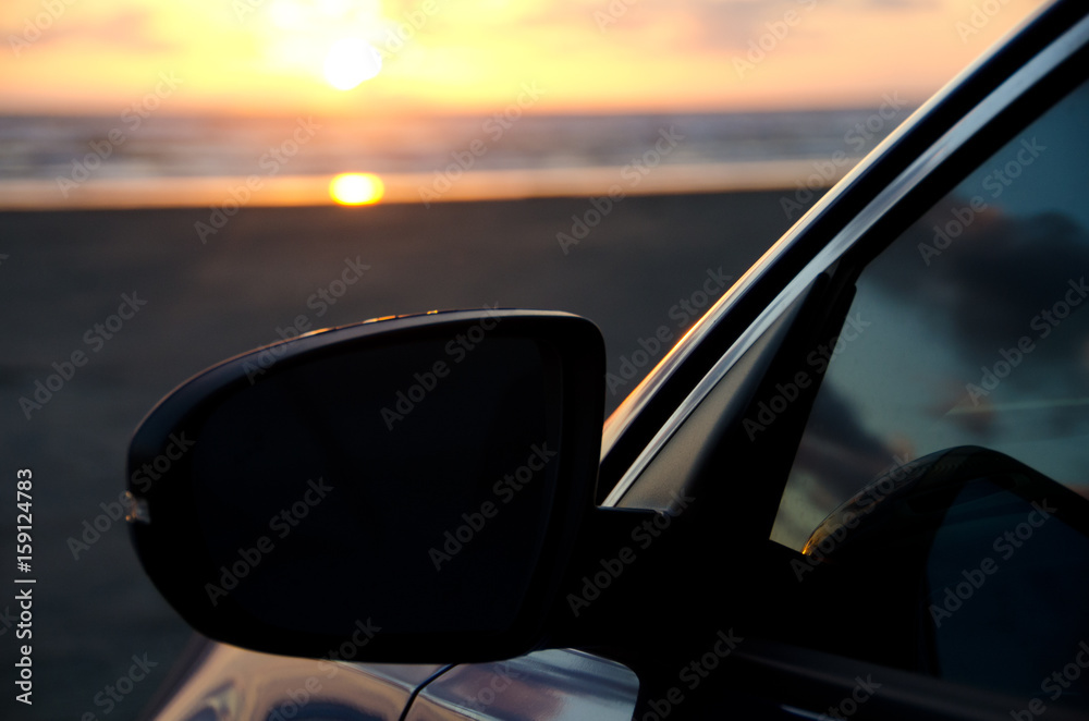 Contrasted mirror of a blue sport sedan under dusk lights at sand beach