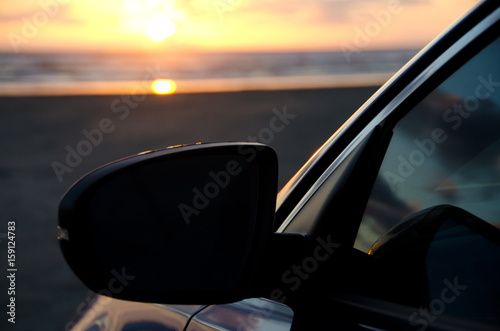 Contrasted mirror of a blue sport sedan under dusk lights at sand beach