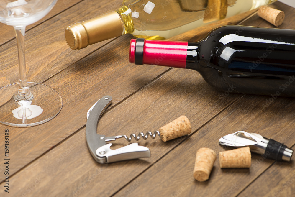 Corkscrew next to a bottle of wine and a glass. Horizontal studio shot.