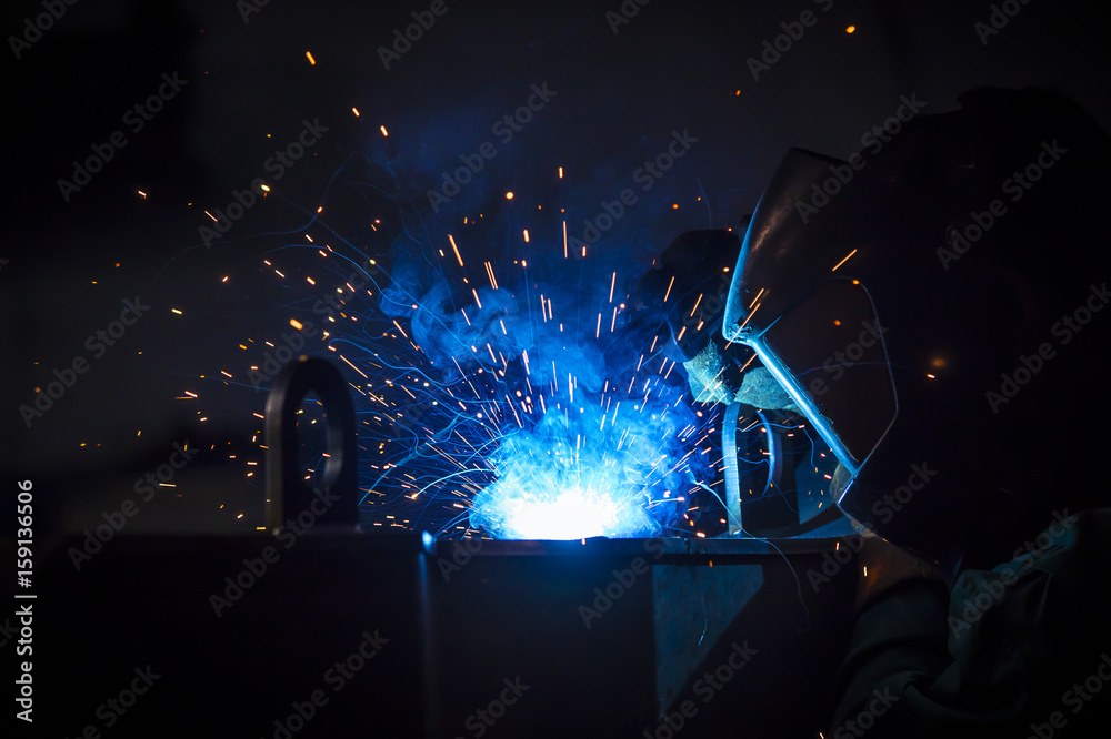 Young industrial worker welding in the factory Young industrial worker welding in the factory