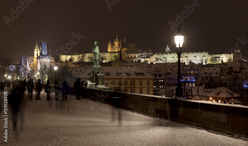 Night snowy Prague Lesser Town with gothic Castle  Bridge Tower and St. Nicholas  Cathedral from Charles Bridge with its baroque Statues  Czech republic