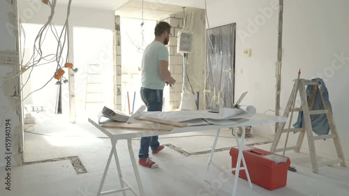 Man working on his project about new flat and measuring walls, steadycam shot
