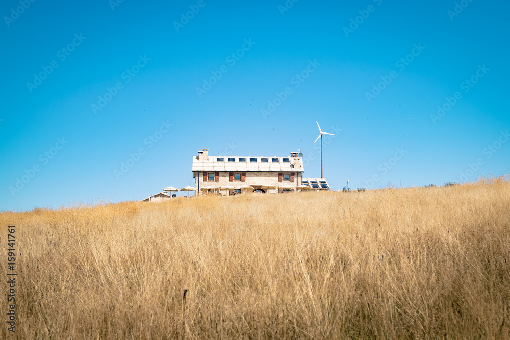 Fototapeta premium Alpine hut with photovoltaic panels and wind generator.