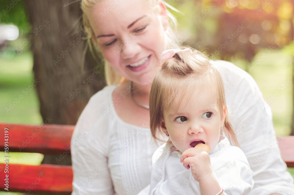 mother and baby sitting on a park bench mother and baby sitting on a park bench