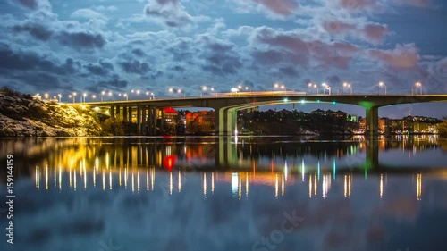 Highway bridge over river at night 4K Time Lapse Tilt. Moonlight and moving clouds, traffic passing by, reflections in the water photo