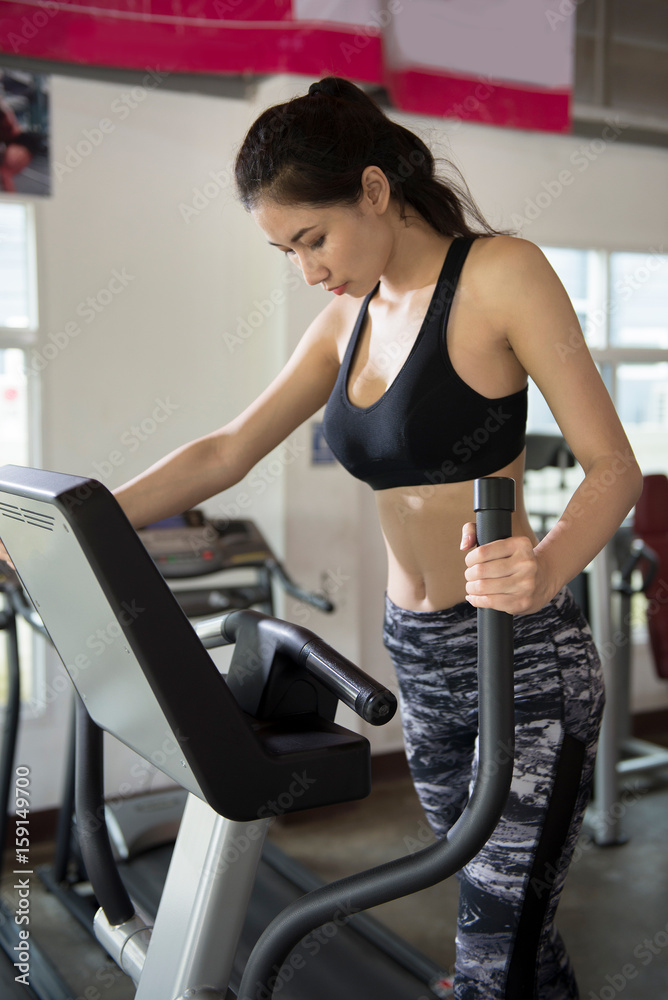 Young asian girl training on Elliptical machine. Concept of health and fitness.