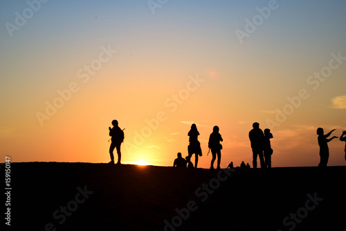 People in desert sunset 