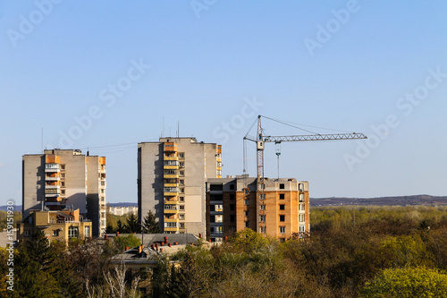 Building crane and building under construction against blue sky © olyasolodenko
