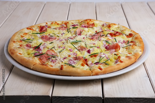pizza with bacon chips, ham, cheese and rosemary