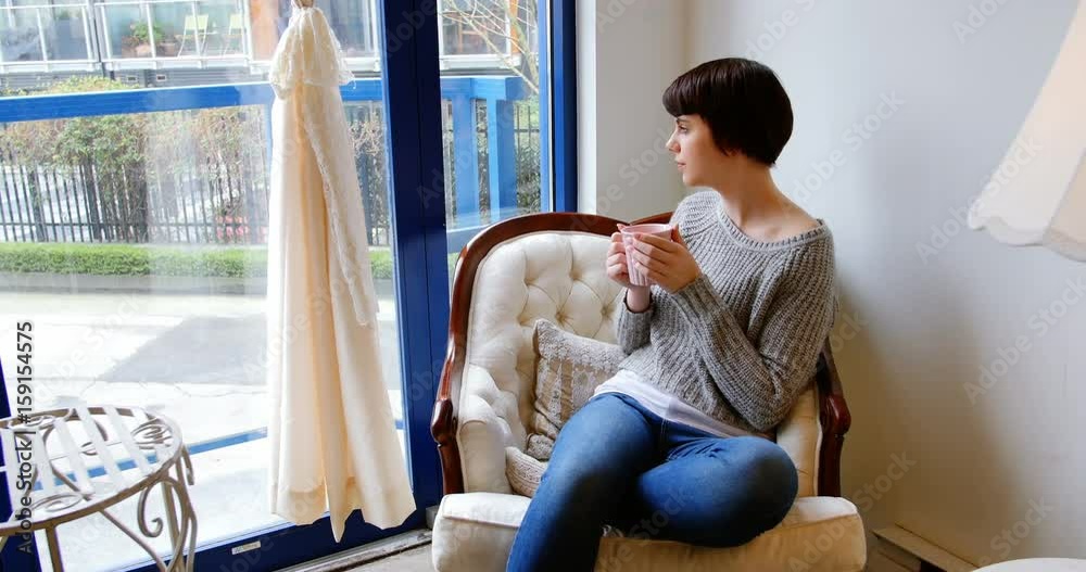 Woman looking through window while having coffee Woman looking through window while having coffee