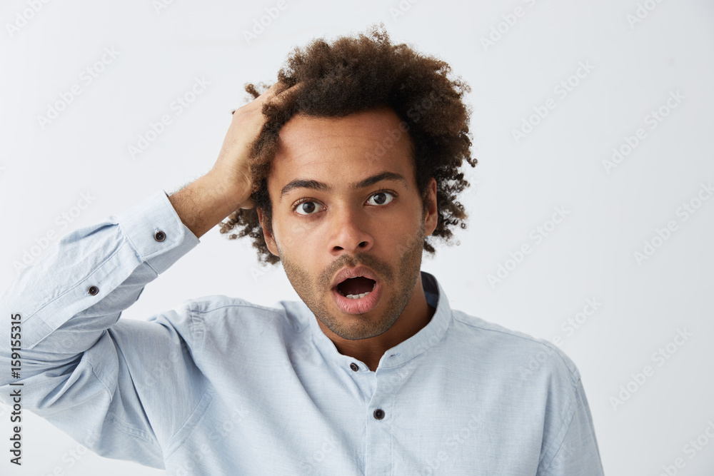 Confused hipster guy with African haitrstyle wearing formal clothes looking at camera with bugged eyes and dropped jaw touching his head with hand realizing his mistakes having shock and surprise Confused hipster guy with African haitrstyle wearing formal clothes looking at camera with bugged eyes and dropped jaw touching his head with hand realizing his mistakes having shock and surprise