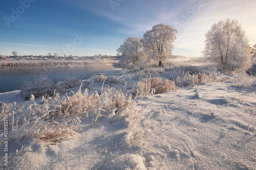 A Real Russian Winter. Morning Frosty Winter Landscape With Dazzling White Snow And Hoarfrost,River And Saturated Blue Sky. Foggy River Bank With Frost-Covered Trees And Crispy Reeds In The Frost..