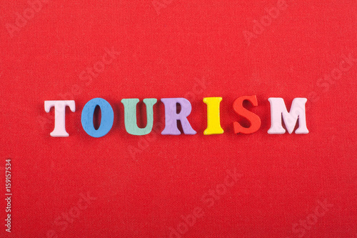 TOURISM word on red background composed from colorful abc alphabet block wooden letters, copy space for ad text. Learning english concept.